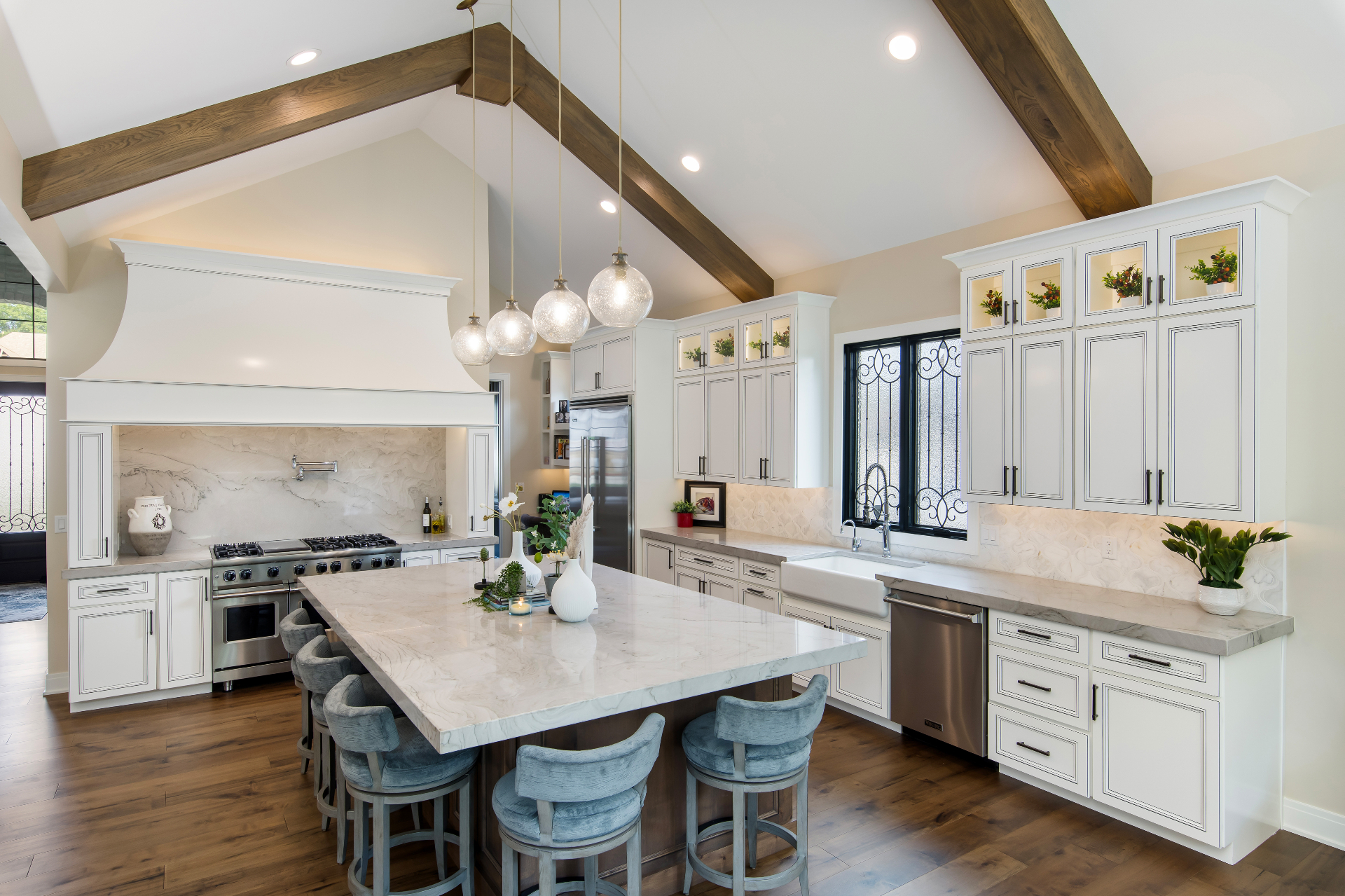 Vaulted kitchen with wood beams, white cabinetry, and marble island