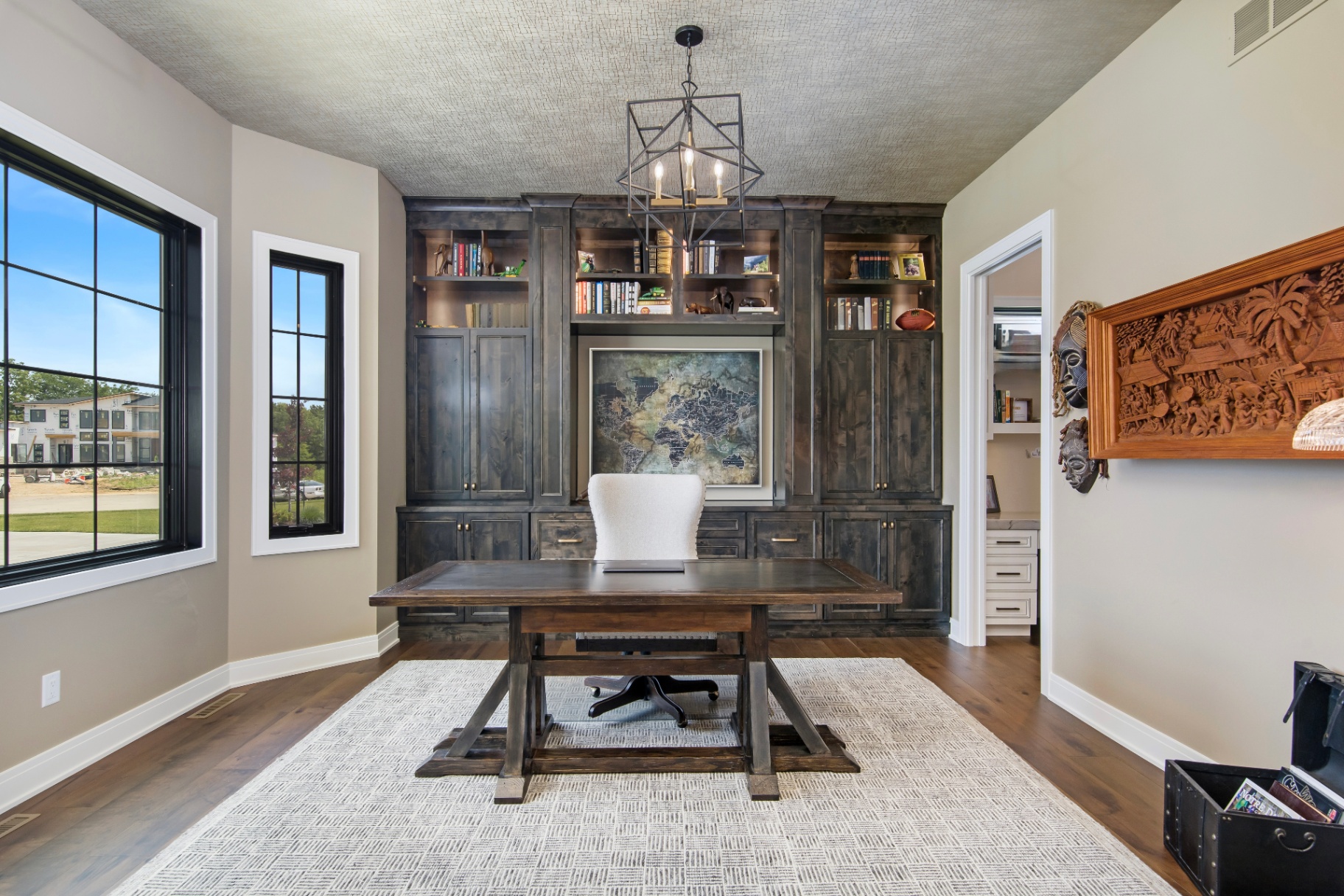 Custom home office with dark stained built-ins and trestle desk