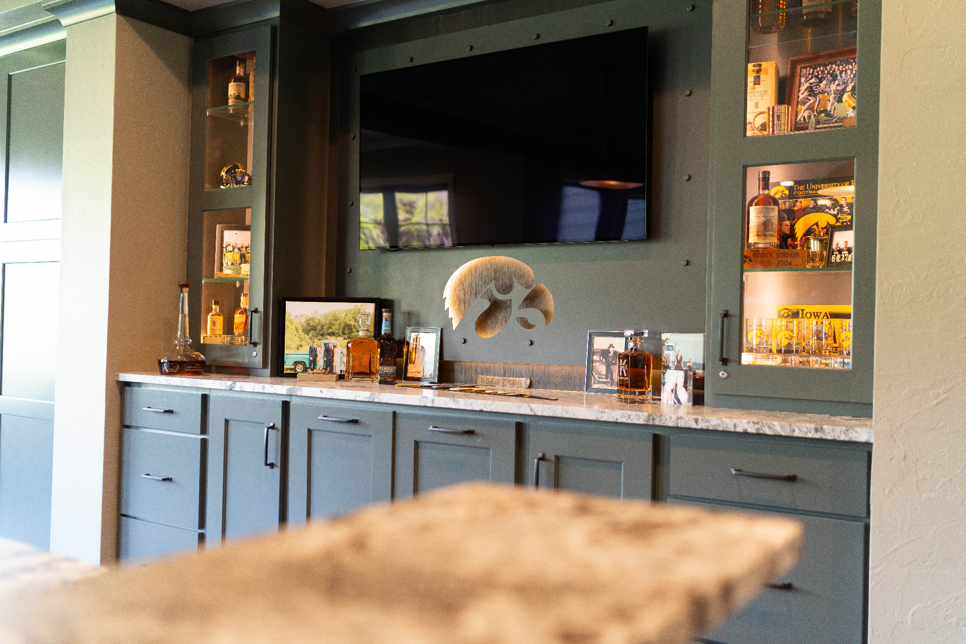 Custom Hawkeye-themed home bar with glass display cabinetry