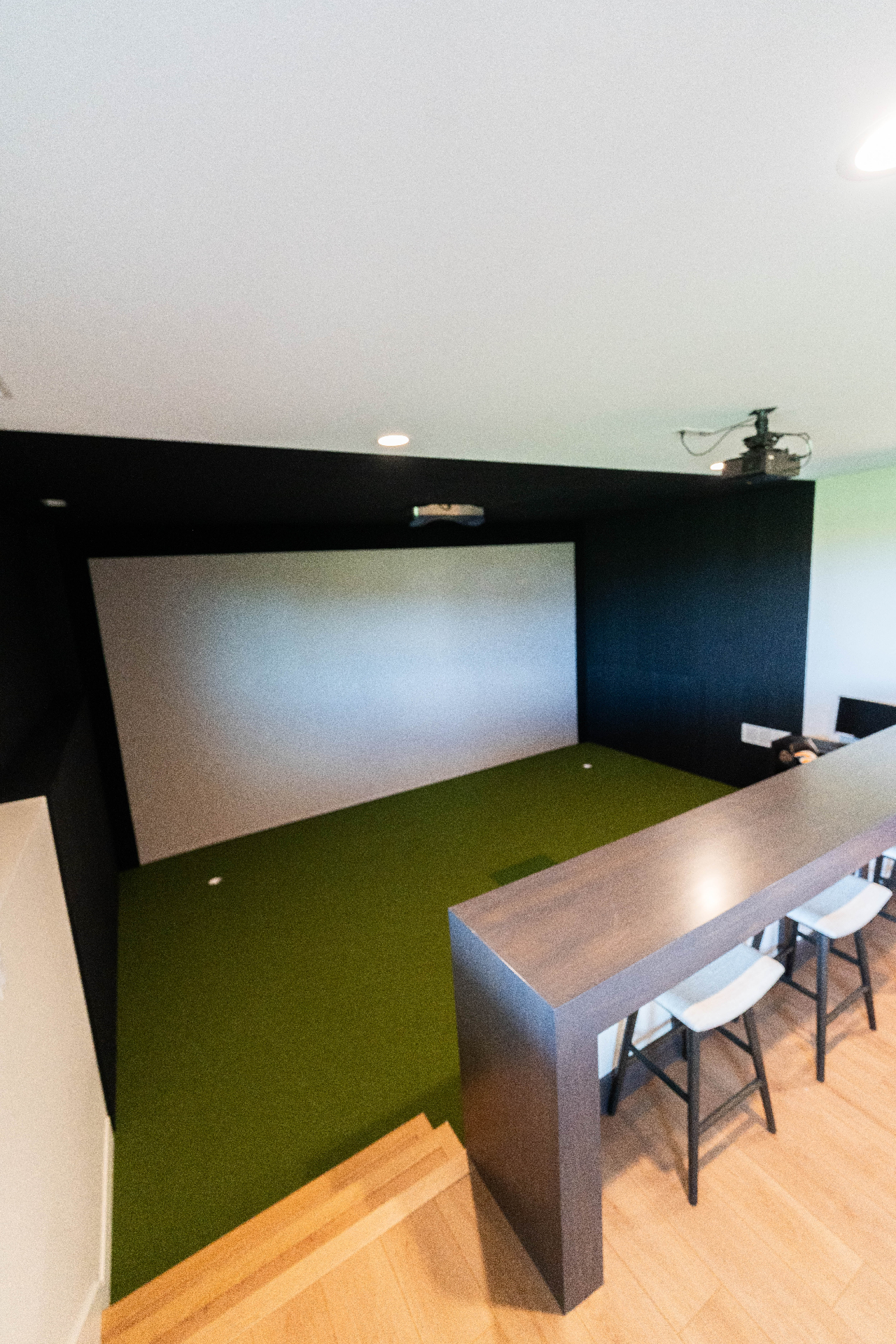 In-home golf simulator room with projector and turf