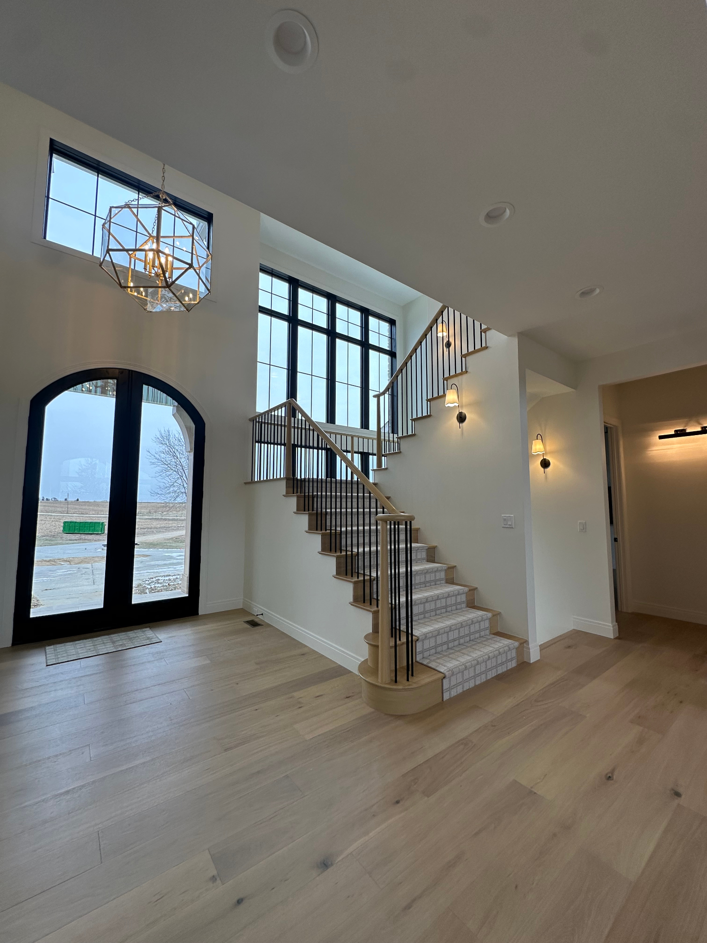 Grand entry with arched double doors and custom staircase